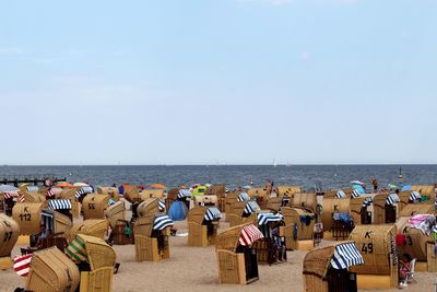 Hooded chairs at beach against clear sky