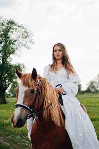 Young woman riding horse on field