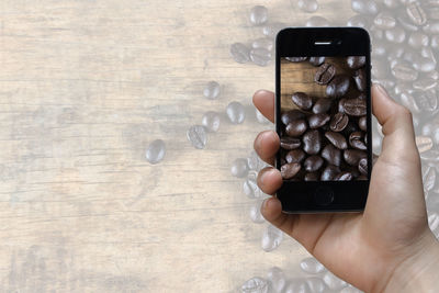 Midsection of man photographing with mobile phone on table