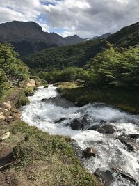 Scenic view of river flowing amidst mountains against sky