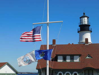 Low angle view of flags against buildings against clear blue sky