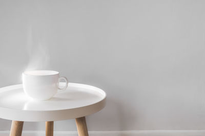 Coffee cup on table against wall