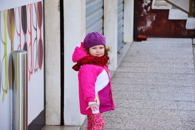 Portrait of cute girl standing on sidewalk during winter