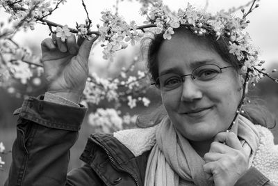 Portrait of smiling woman holding flowers on tree