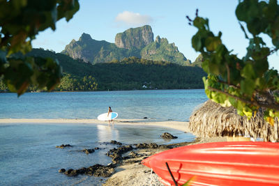 Mid distance view of man with surfboard walking at beach