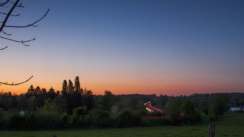 Trees on landscape against clear sky