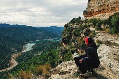 Side view of woman with dog while crouching on mountain