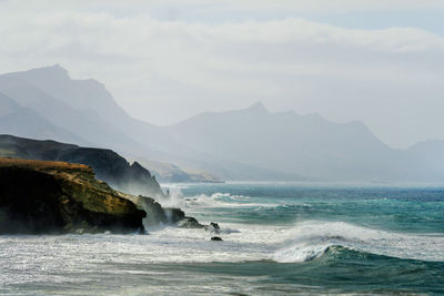 Scenic view of sea and mountains against sky