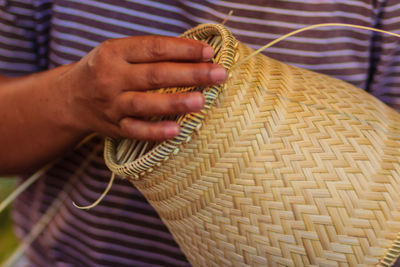 Midsection of man making wicker decoration