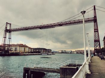 Vizcaya bridge over nervion river against cloudy sky