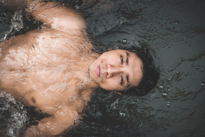 High angle portrait of shirtless man swimming in stream