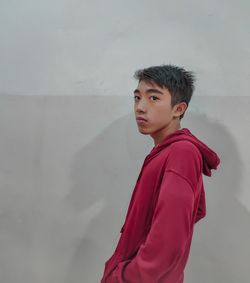 Portrait of young man looking away against wall