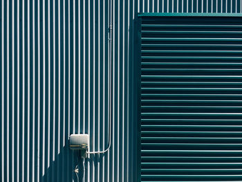 Security camera on striped wall during sunny day