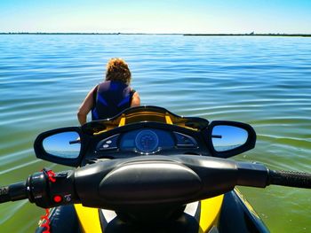 Rear view of woman with jet boat in sea against sky