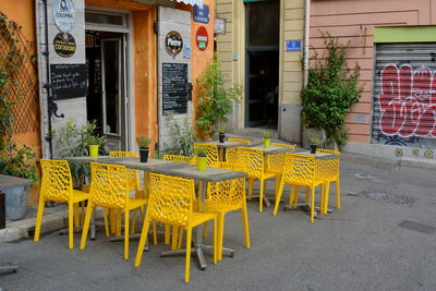 Empty chairs and tables at sidewalk cafe in city