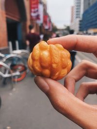 Midsection of woman holding sweet food on street in city