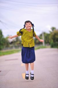 Cheerful girl jumping on road