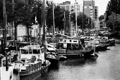 Boats moored at harbor against buildings in city