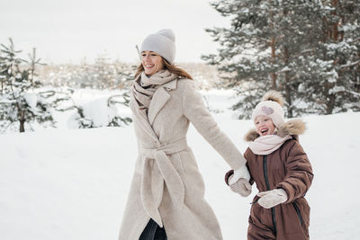 Mother and daughter have fun running in the snowy forest. high quality photo
