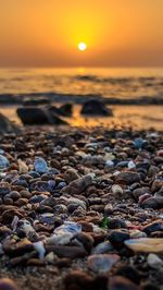 Close-up of pebbles at beach against sky during sunset