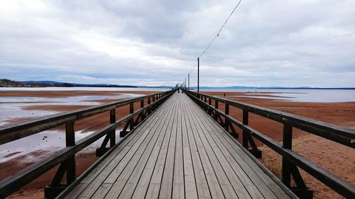 Pier on sea against cloudy sky