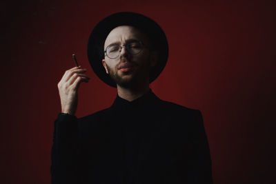 Portrait of young man standing against black background