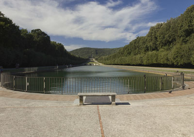 Empty swimming pool by lake against sky