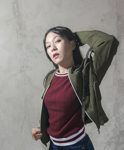 Beautiful young woman standing against wall