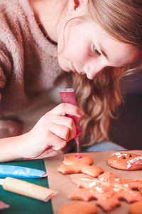 Girl decorating christmas gingerbread cookies at home