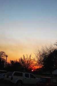 Cars on street against sky at sunset