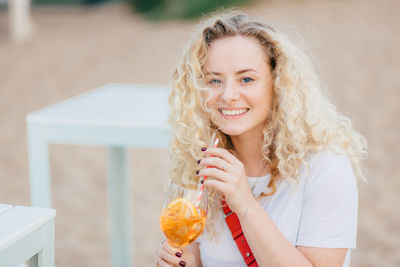 Portrait of a smiling young woman drinking glass