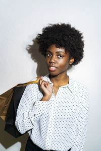 Young woman carrying shopping bags while standing against white background