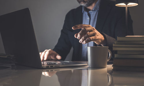 Midsection of man using laptop on table