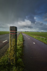 Road sign on field against sky