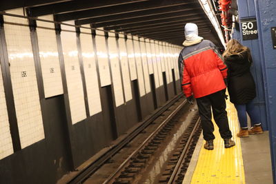 Rear view of woman standing on railroad station platform