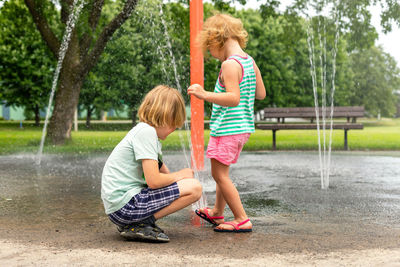 Small beautiful kids having fun at fountain playground in park