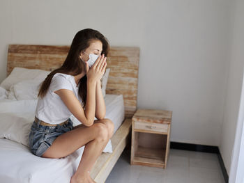 Woman sitting on bed at home