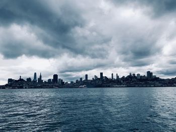 Sea by buildings against sky in city