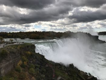 Scenic view of niagara falls against cloudy sky