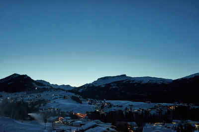 Houses on snowcapped mountain against clear blue sky