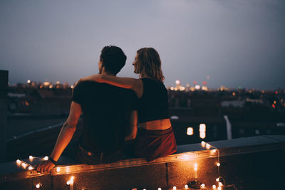 Rear view of couple kissing against sky at night