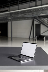 Laptop with blank screen on desk at industial hall