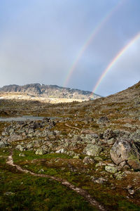 Scenic view of rainbow over mountain against sky