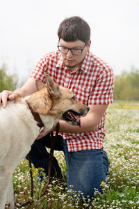 Pet examining and care. young man examining his mixed breed shepherd dog 