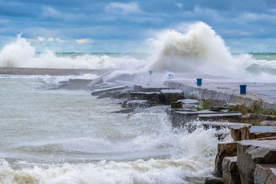 Waves splashing on shore against sky