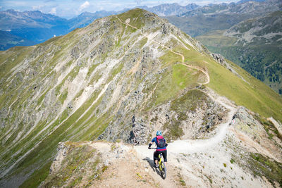 Rear view of man riding bicycle on mountain