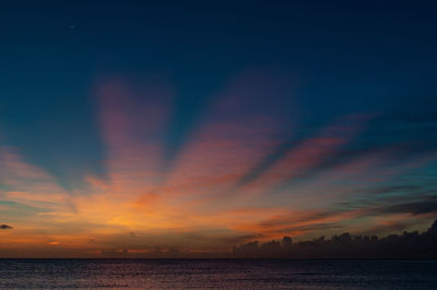 Scenic view of sea against dramatic sky during sunset