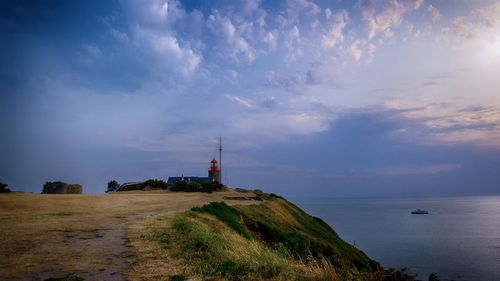 Lighthouse amidst sea and buildings against sky