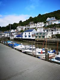 Sailboats moored on sea by buildings in city against sky