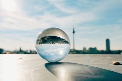 Close-up of crystal ball against sky